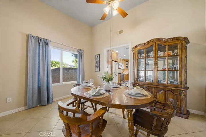 Large window faces west (side yard). Formal living room with ceiling fan and high ceilings. Throughway to the kitchen. another throughway (not shown in the image) leads to the family adjacent to the kitchen.