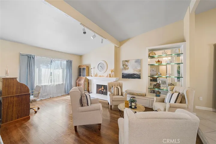 Formal living room with built in shelves with lighting and side bench. Fireplace provides ambiance and adds warmth to conversations. Fire is photoshopped in fireplace. One step up to the right of the image to the formal dining area.