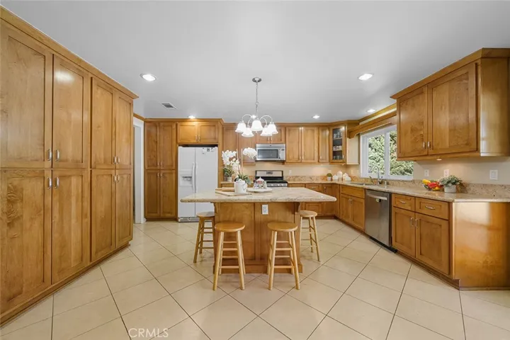 An inviting updated kitchen, at one time, reimagined with extra cabinets for pantry needs and room to enjoy as extra living room. Island in the middle is a great gathering hub with granite counters.