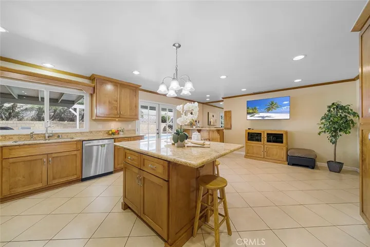 Spacious area beyond the island to have as a second living area. Recessed lighting and updated kitchen, at one time, wet bar in the distance all help make this area an inviting space to gather.