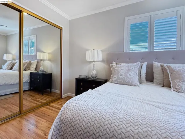 Bedroom with crown molding, light wood finished floors, and a closet