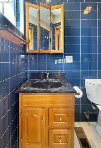 Bathroom featuring tile walls, vanity, and light tile patterned floors