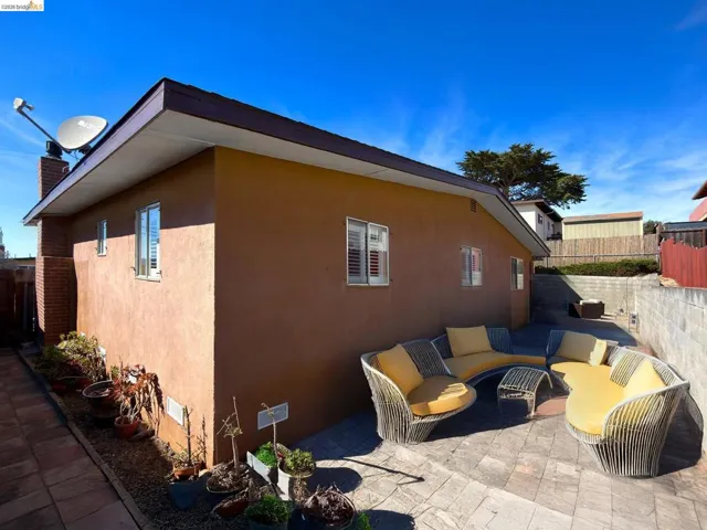 View of side of home featuring an outdoor lounge area, stucco siding, a patio, and a chimney