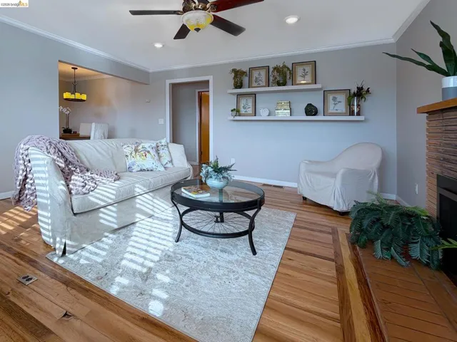 Living area with ornamental molding, a fireplace, wood-type flooring, a ceiling fan, and recessed lighting