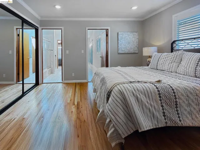 Bedroom featuring ornamental molding, a closet, light wood-style flooring, and ensuite bath