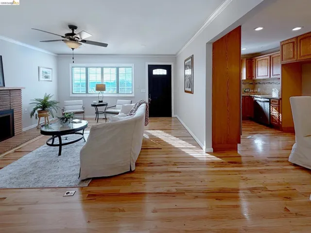 Living area featuring a ceiling fan, light wood-style flooring, ornamental molding, a brick fireplace, and recessed lighting