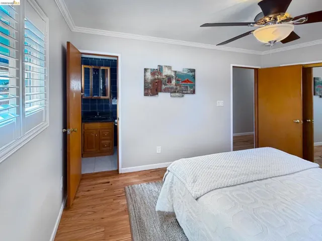 Bedroom with light wood finished floors, ceiling fan, and crown molding
