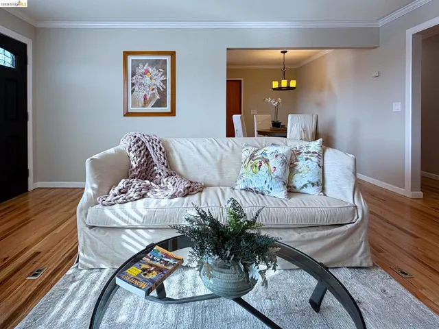 Living area with ornamental molding and light wood-style floors