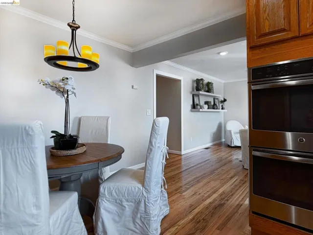 Dining room with ornamental molding, light wood finished floors, and suspended lighting