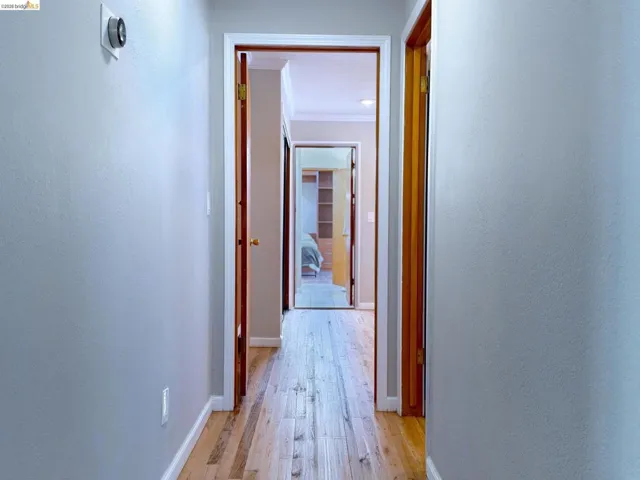 Hallway featuring light wood-type flooring and ornamental molding