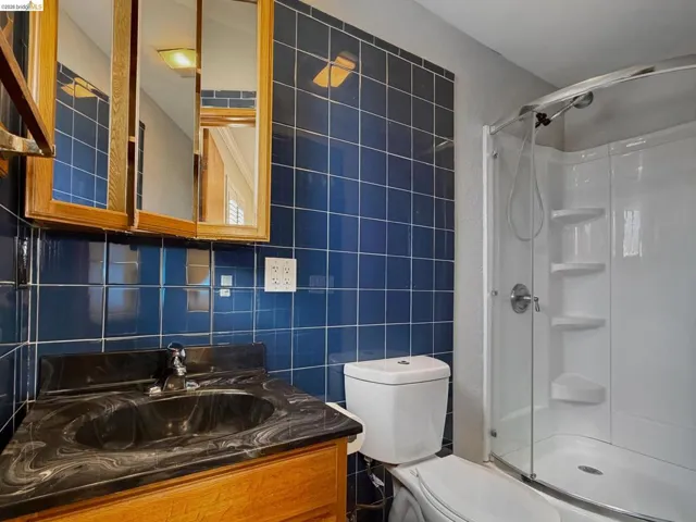 Bathroom featuring tile walls, vanity, and a shower stall