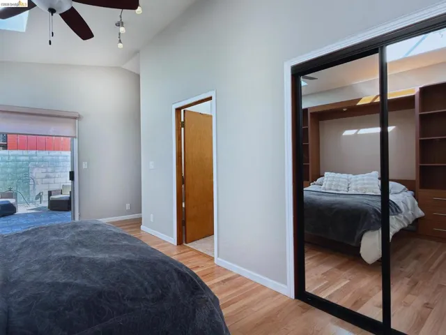 Bedroom featuring light wood-style flooring, vaulted ceiling, ceiling fan, access to exterior, and rail lighting