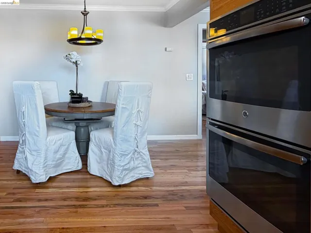 Dining space with light wood-style flooring, hanging lights, and crown molding