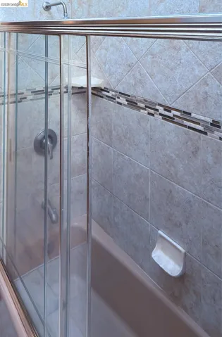Bathroom with bath / shower combo with glass door