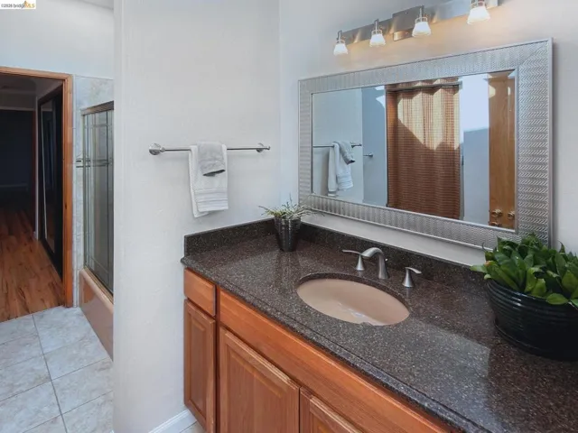 Bathroom with vanity, shower / bath combination with glass door, and light tile patterned flooring