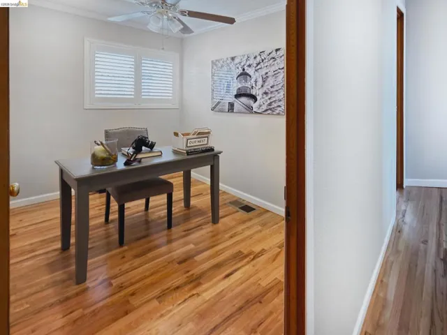 Office area featuring ornamental molding, light wood-type flooring, and a ceiling fan