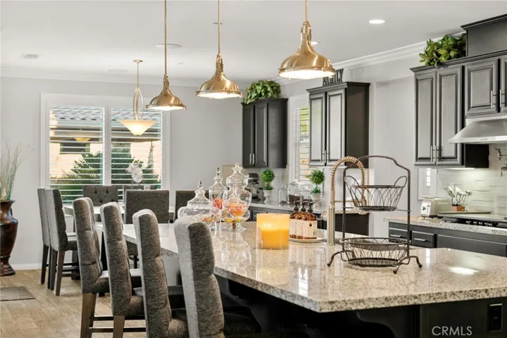 Luxurious custom kitchen and great room:
This expansive, open-concept great room showcases a designer kitchen with premium stainless-steel appliances, double ovens, sleek pendant lighting, and abundant cabinetry. A spacious island with generous counter seating anchors the space, seamlessly flowing into the elegant living area and a large dining niche—perfect for entertaining. Sliding glass doors open to the resort-style backyard, creating the ultimate indoor-outdoor living experience.