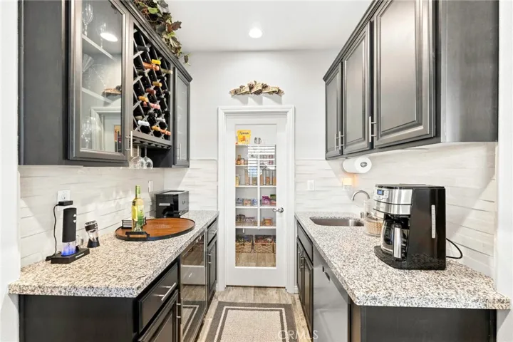 Elegant butler’s pantry featuring a built-in wine refrigerator, custom wine storage, sink, and a generous walk-in pantry. Designed for effortless entertaining and refined functionality.