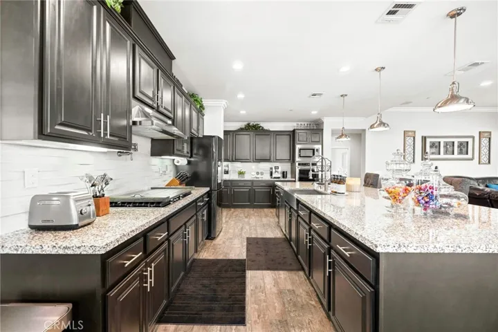 Luxurious custom kitchen and great room:
This expansive, open-concept great room showcases a designer kitchen with premium stainless-steel appliances, double ovens, sleek pendant lighting, and abundant cabinetry. A spacious island with generous counter seating anchors the space, seamlessly flowing into the elegant living area and a large dining niche—perfect for entertaining. Sliding glass doors open to the resort-style backyard, creating the ultimate indoor-outdoor living experience.