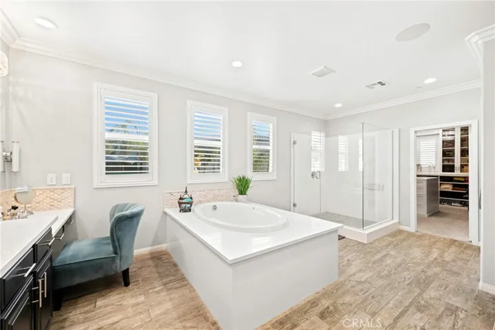 Luxurious primary spa retreat:
This expansive primary bathroom offers a true spa-like experience, featuring a deep soaking tub framed by natural light streaming through the windows. Elegant tile flooring, soaring ceilings, and dual vanities create an atmosphere of sophistication, while a separate dressing area provides comfort and privacy for daily routines.