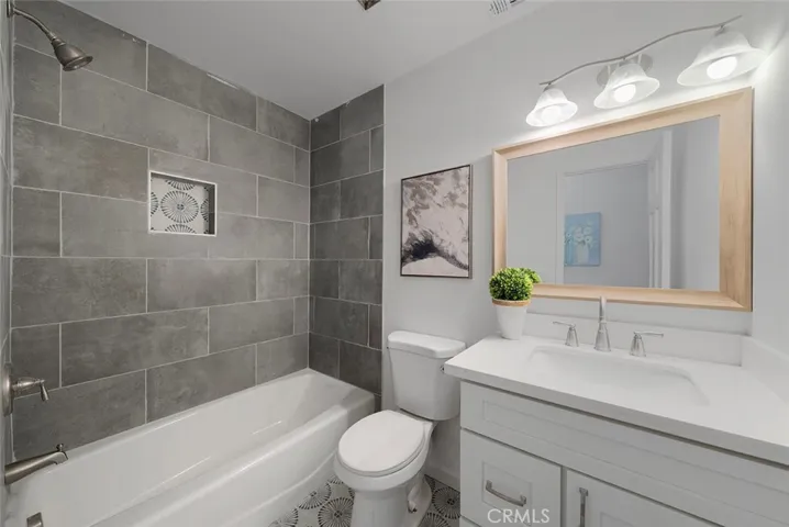 Newly updated hallway bathroom with cast iron tub, stylish tile, fixtures, cabinet, sink, toilet.