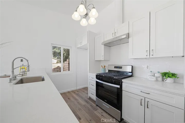 Open galley style kitchen that has been thoughtfully reimagined to accommodate today's styles and needs. Room for a refrigerator at the corner by the window. Newer stove, hood, sink, dishwasher, fixtures, subway tile, soft close cabinets and drawers.