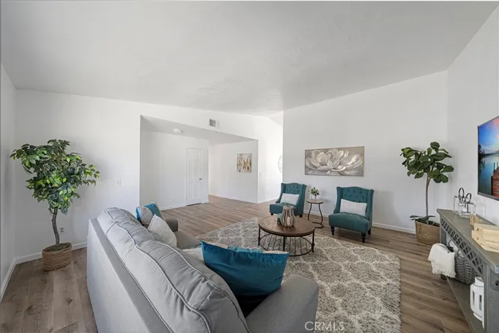 Spacious living room with newer luxury vinyl plank flooring. Newly painted and newer double pane flooring. Ceiling height gets to about 10 feet. Hallway to bedrooms pass the closet door. Throughway to the right leads to the kitchen/dining.