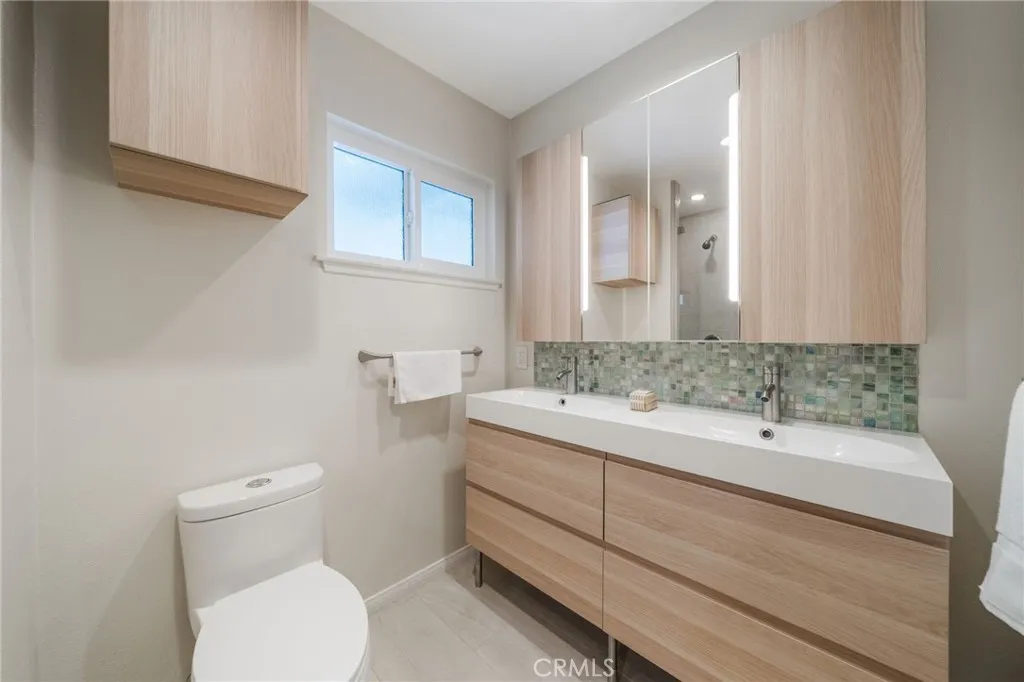 Beautiful pale oak plank cabinetry with irridecesnt back splash.