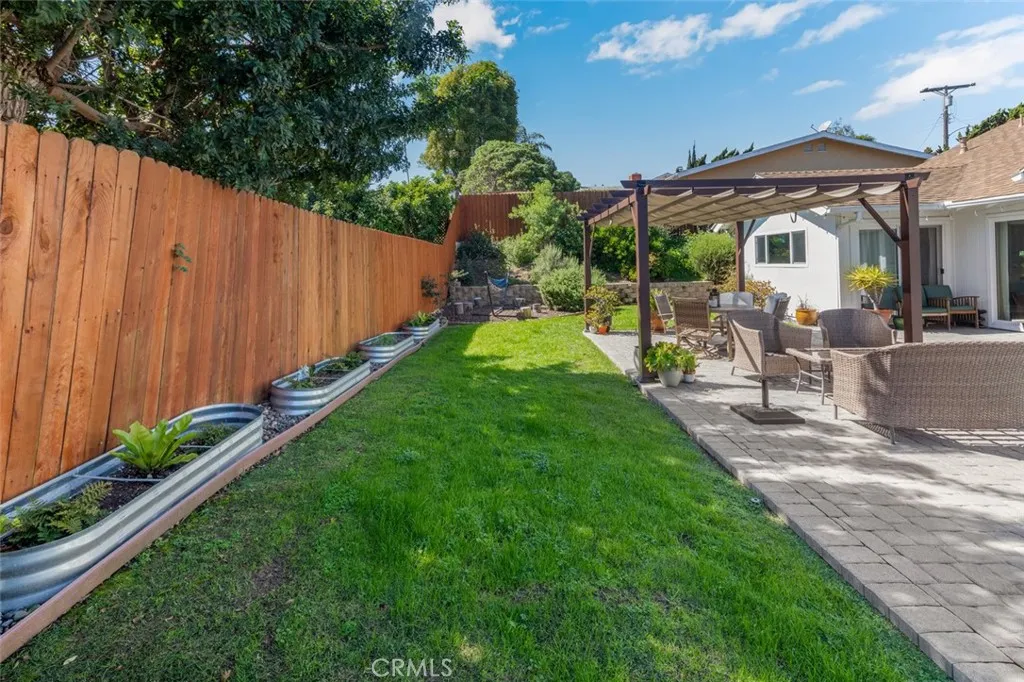 There is a large grass area behind the pergola.