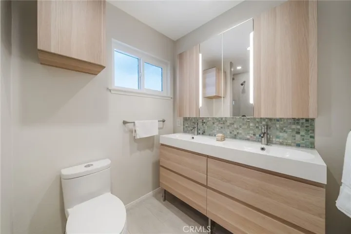 Beautiful pale oak plank cabinetry with irridecesnt back splash.