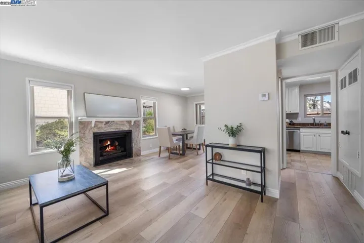 A stunning, sunlit, cozy living room with a fireplace, offering an inviting ambiance. Per AB 723 - Fire in fireplace has been digitally rendered.