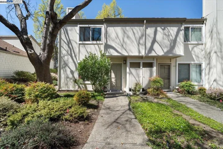 Fresh exterior paint and lush foliage lead to a private walk-up, offering a charming entrance.