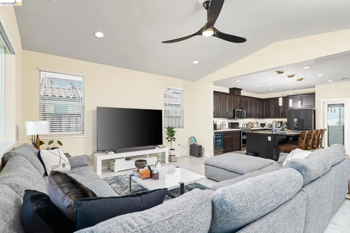 Living room with a ceiling fan, recessed lighting, vaulted ceiling, and beverage cooler