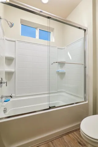 Bathroom featuring bath / shower combo with glass door and wood finished floors