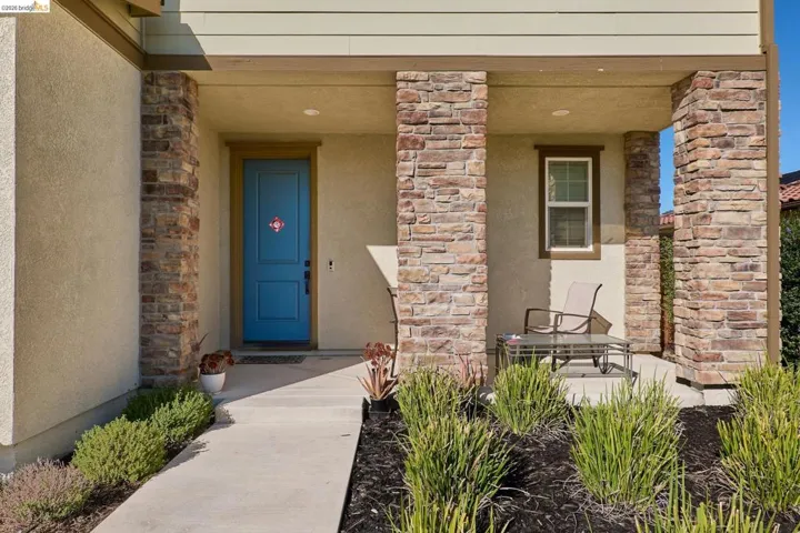 View of exterior entry with covered porch, stucco siding, and stone siding