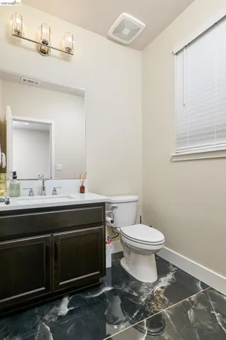 Half bathroom with vanity and dark marble finish flooring