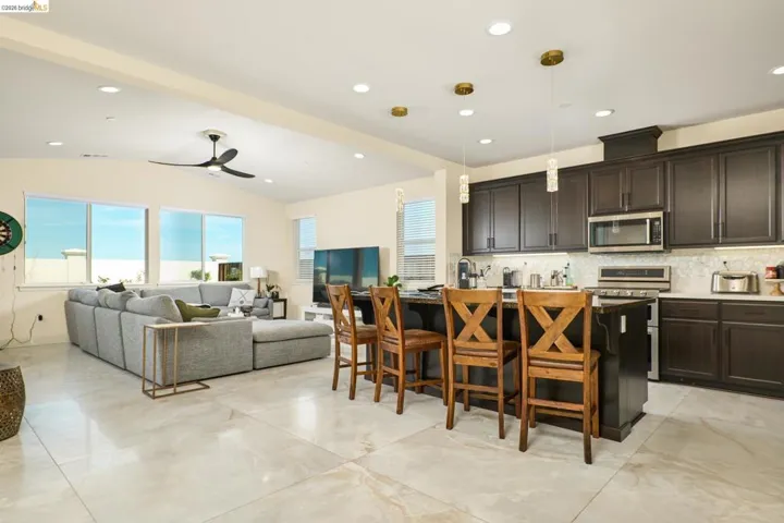 Kitchen with a breakfast bar, a center island with sink, stainless steel appliances, decorative backsplash, and healthy amount of natural light