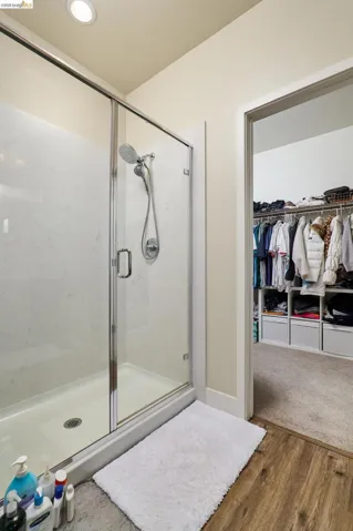 Full bath featuring a walk in closet, wood finished floors, a shower stall, and recessed lighting