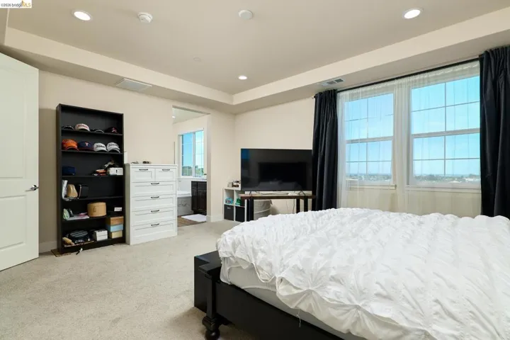 Bedroom with light colored carpet, recessed lighting, and connected bathroom