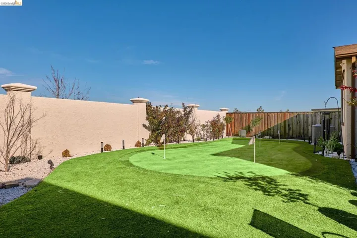 Fenced backyard featuring a putting green