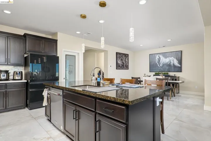 Kitchen featuring dark wood finish cabinetry, dark stone counters, smart refrigerator, and pendant lighting