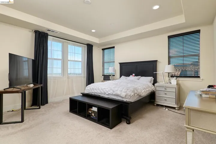 Bedroom featuring light carpet, a tray ceiling, and recessed lighting