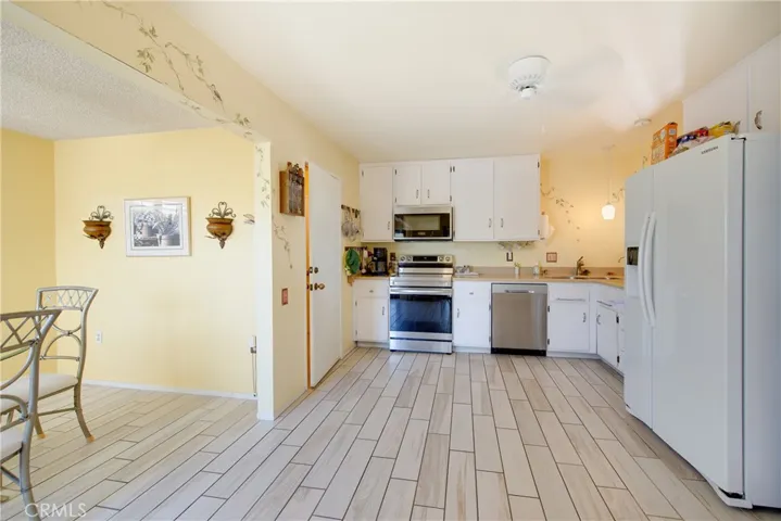 Remodeled kitchen with wood like tile floors, custom countertops newer appliances.