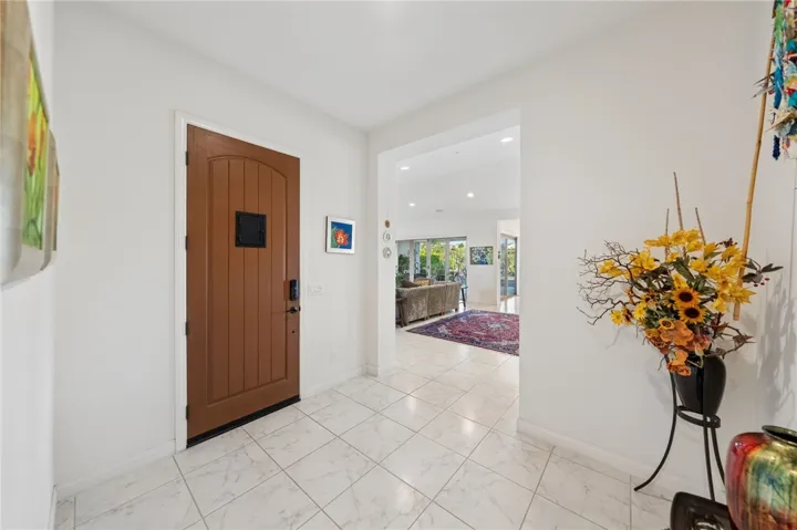 Light-filled foyer welcomes guests with high ceilings, oversized tile flooring, and an easy flow into the main living areas.