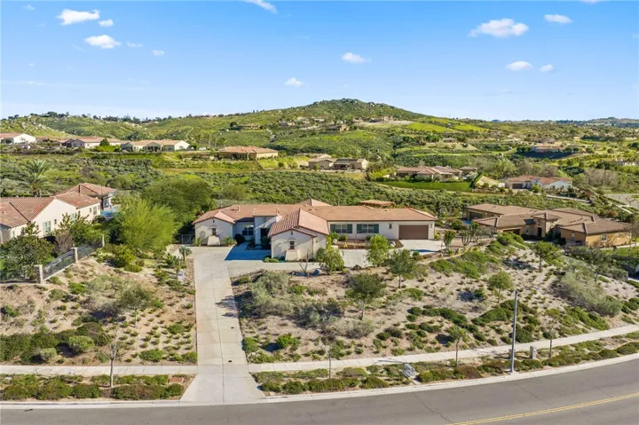 Elevated lot placement highlights the home’s expansive footprint, long driveway, and surrounding hillside views.