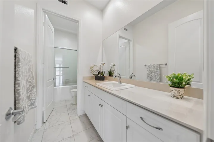 Bright secondary bath features an extended single-sink vanity, ample counter space, and a clean, well-kept design.