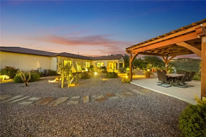 Thoughtfully designed backyard features wide gravel pathways, accent lighting, and multiple areas to gather and unwind.
