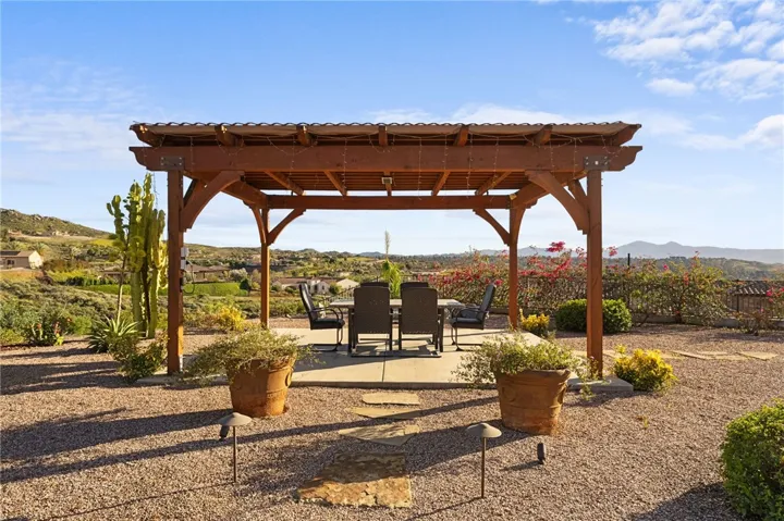 Freestanding pergola creates an inviting outdoor dining space with wide-open hillside and neighborhood views.