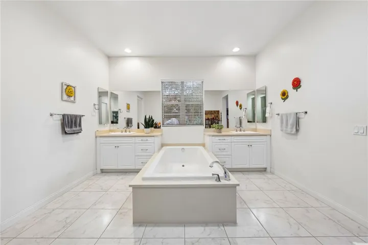 Symmetrical dual-sink vanities and a centrally placed soaking tub create a clean, spa-inspired retreat.