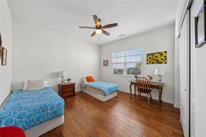 Generously sized bedroom includes wood flooring, ceiling fan, and space for two beds or a variety of furniture layouts.